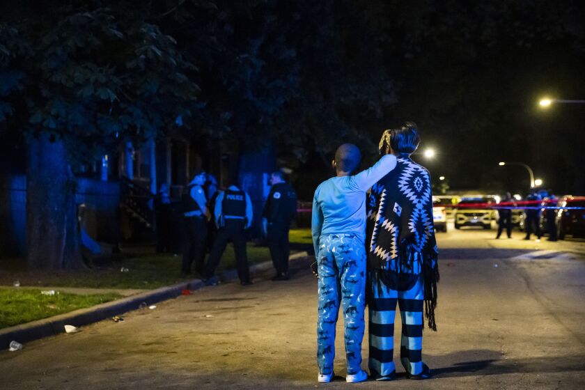 Family members watch as Chicago police investigate in the 5700 block of South Carpenter Street, where a man was shot to death early Sunday during a party on the Englewood neighborhood block on the South Side.